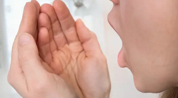 Kobieta sprawdza oddech, obawiając się, że czuć od niej smród z zęba.
